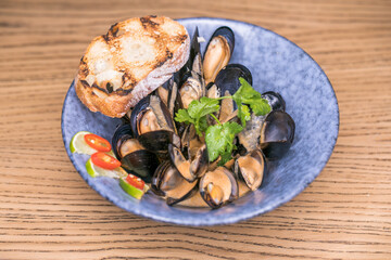 restaurant dish in shell mussels with sauce in a blue plate