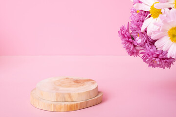 Wooden podium or pedestal with chrysanthemum flowers on pink background. Mockup for your cosmetic products