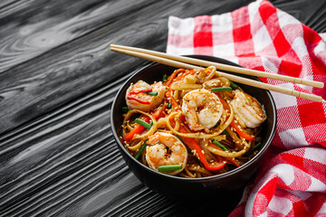 fried wok shrimp noodles on a black wooden rustic background