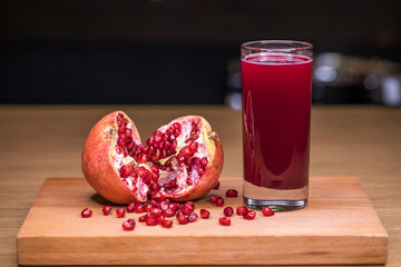 a glass of freshly squeezed juice and ripe pomegranate seeds