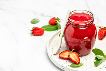 Strawberry jam in the glass jar with fresh berries on white table. Long banner format