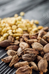 a barrel of dried black cardamom on a black wooden rustic background