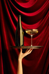 Traditional luxury taste. Bottle and glass with champagne over dark red silk background....