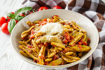 green cavatelli pasta with spinach in tomato sauce on a white wooden background