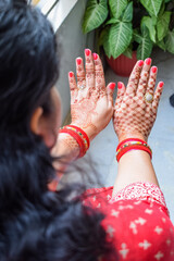 Beautiful woman dressed up as Indian tradition with henna mehndi design on her both hands to...