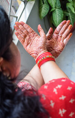 Beautiful woman dressed up as Indian tradition with henna mehndi design on her both hands to...