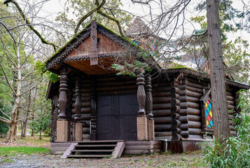 Fototapeta na wymiar Wooden house with carved columns and platbands in the forest