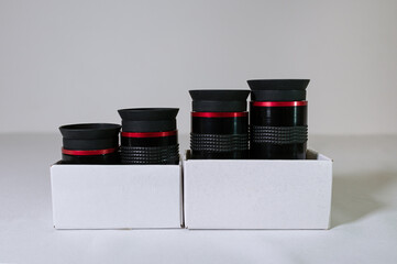 Black telescope eyepieces in a white box close-up on a white background. Optical lenses - accessory...