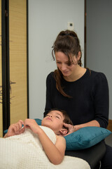 Caucasian woman practicing osteopathy on a child