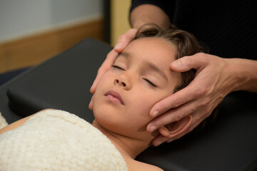 Caucasian woman practicing osteopathy on a child