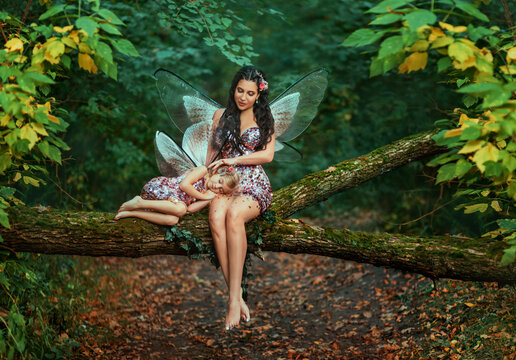 Fantasy woman fairy, sitting on log stroking with love sleeping little girl. Pixie is dreaming. Mom reads fairy tale to daughter, sings lullaby. family shooting motherhood care. trees summer forest
