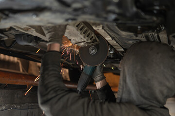 Cuts off the catalyst on the vehicle, sparks fly. Selective focus. Man repairing of corrugation...