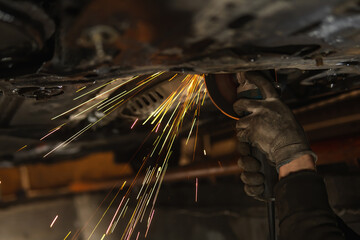 Cuts off the catalyst on the vehicle, sparks fly. Selective focus. Man repairing of corrugation...