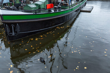 Old boat on the river with fallen leaves on a cloudy autumn day.