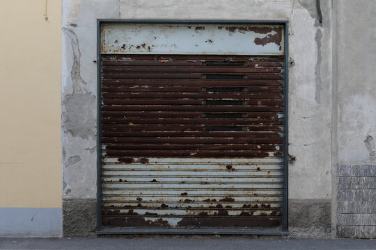 Industrial house wall with two looked roller doors, metal jalousie brown and rusty, no person