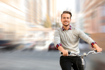 Handsome happy man riding bicycle on city street, motion blur effect