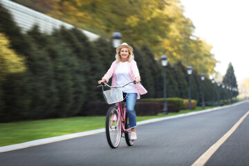 Mature woman riding bicycle outdoors, motion blur effect