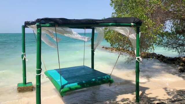 Luxury beach cabana with green canopy and comfortable daybed overlooking turquoise ocean water on tropical paradise island resort