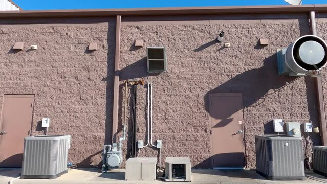 Industrial air condition units and exhaust back of retail strip mall building clear blue sky