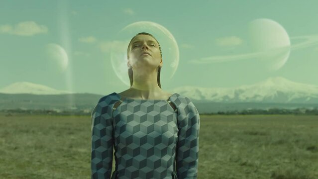 Portrait of stylish woman with futuristic space helmet standing , dreaming on field . Surreal extraterrestrial landscape . Concept of fantasy mystic dream . Planets at day in the sky . Surrealism