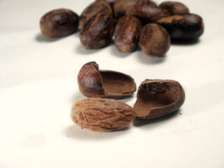 Heap of whole dried nutmeg seeds close up isolated on white background