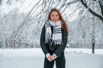 Fototapeta na wymiar In the warm scarf. Beautiful young woman is outdoors in the winter forest
