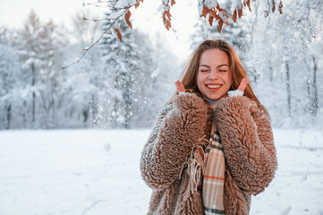 In fur coat. Beautiful young woman is outdoors in the winter forest