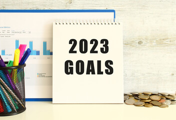 A notebook with the text 2023 GOALS is leaning against the wall with a folder with charts.