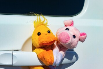 Muñecos de pato naranja y cerdo rosa encima de un tirador de un coche