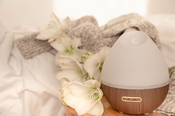 Spa composition with aroma diffuser and lily flowers close-up.