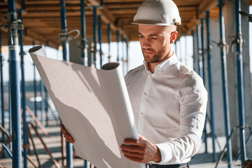 Standing and reading plan. Man is working on the construction site at daytime