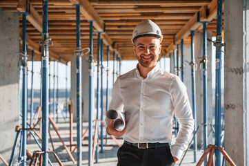 Standing and smiling. Man is working on the construction site at daytime