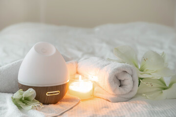 Cozy spa composition with aroma diffuser, candle and flowers.