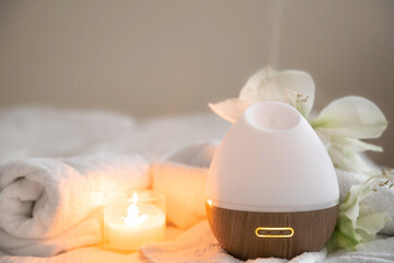 Cozy spa composition with aroma diffuser, candle and flowers.