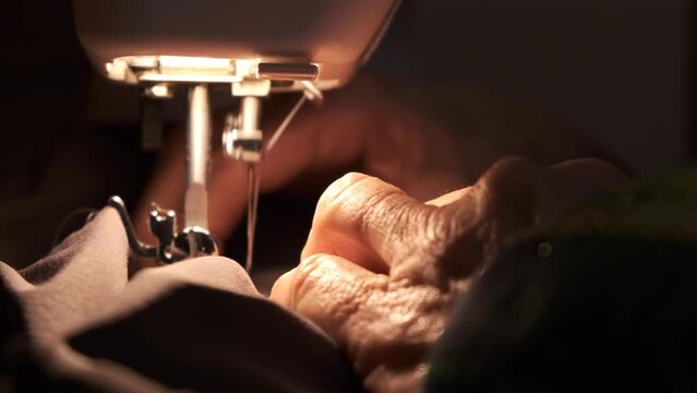 Sewing machine working. Needle in motion. close-up of sewing machine needle quickly moves up and down. Old woman working. The process of sewing the fabric.
