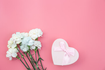 Bouquet of flowers, heart shaped gift box on pink background, flat lay.