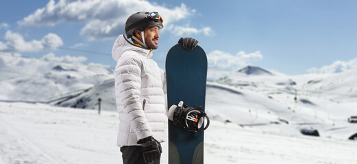 Profile shot of a man standing with a snowboard