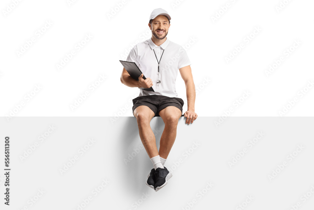 Sticker Full length portrait of a sports coach holding a clipboard and sitting on a blank panel