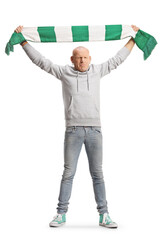 Full length portrait of a man cheering with a green and white scarf