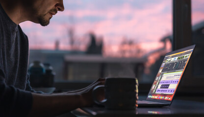 A man works with sound on a laptop early in the morning. - obrazy, fototapety, plakaty