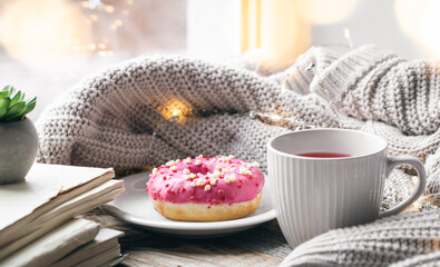 Cozy composition with a donut, a cup of tea and a knitted element.