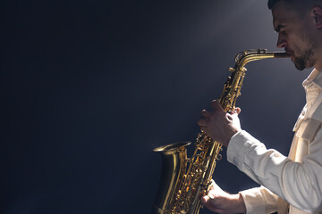 Fototapeta na wymiar A European man plays the saxophone in the dark.