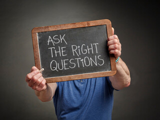 ask the right questions - white chalk text on a slate blackboard held by a person,  education,...
