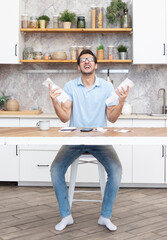 Close up of unhappy man sitting at the table, stressed and confused by calculate expense from invoice or bills, have no money to pay mortgage or loan. High prices and spending money concept