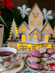 Christmas table decoration with gingerbread, hot tea, Christmas flower and wooden house 