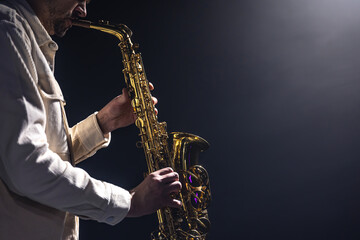 Obraz na płótnie Canvas A European man plays the saxophone in the dark.