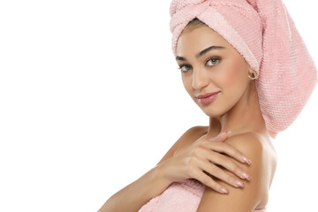 A pretty smiling young woman with towel on her head posing on a white background