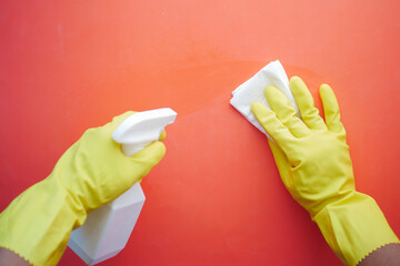 hand in yellow rubber gloves holding spray bottle cleaning table 