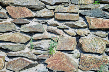 The texture of the masonry wall of natural stone. Detail of a stone wall with different size of rocks.
