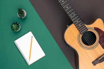 Flat lay, acoustic guitar and notebook on color background.